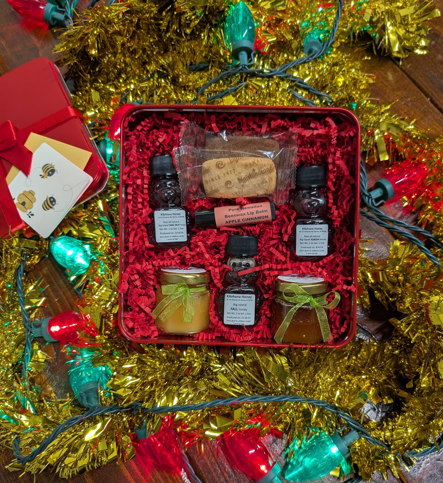 Gift set with jars and bottles in a red box surrounded by Christmas decorations.